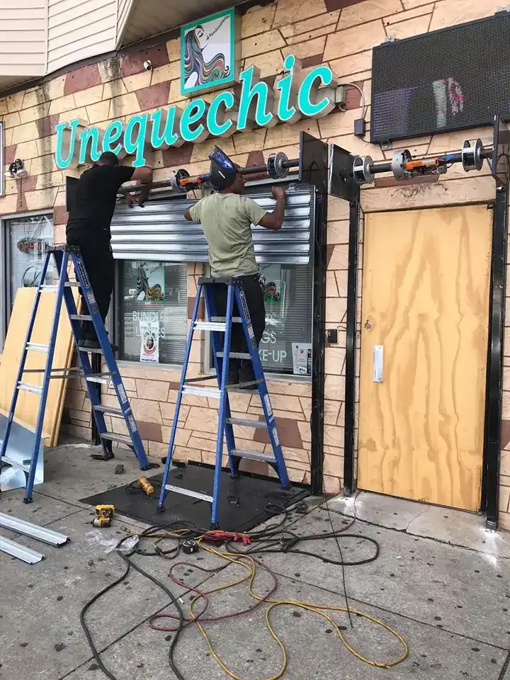 Philly Rolling Gates crew installing a storefront rolling gate from ladders
